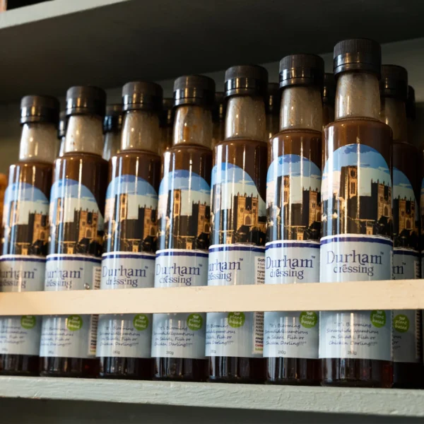 seven bottles of durham dressing lined up on a shelf.